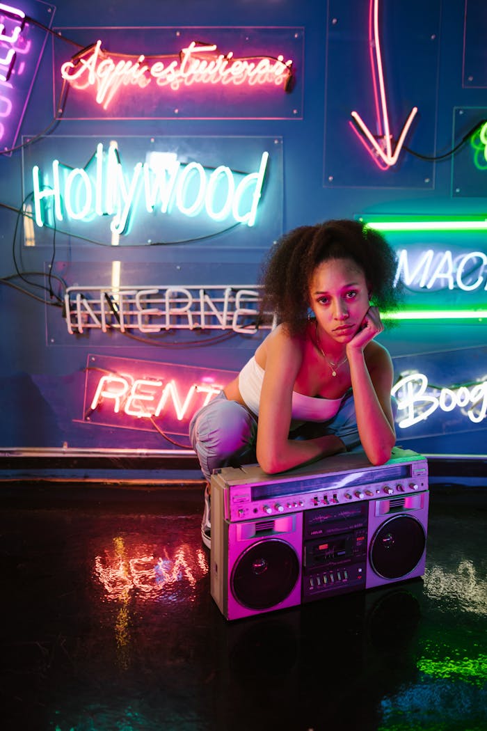 about-us Young woman in a neon-lit room with a vintage boombox, embodying vibrant nightlife and urban culture.